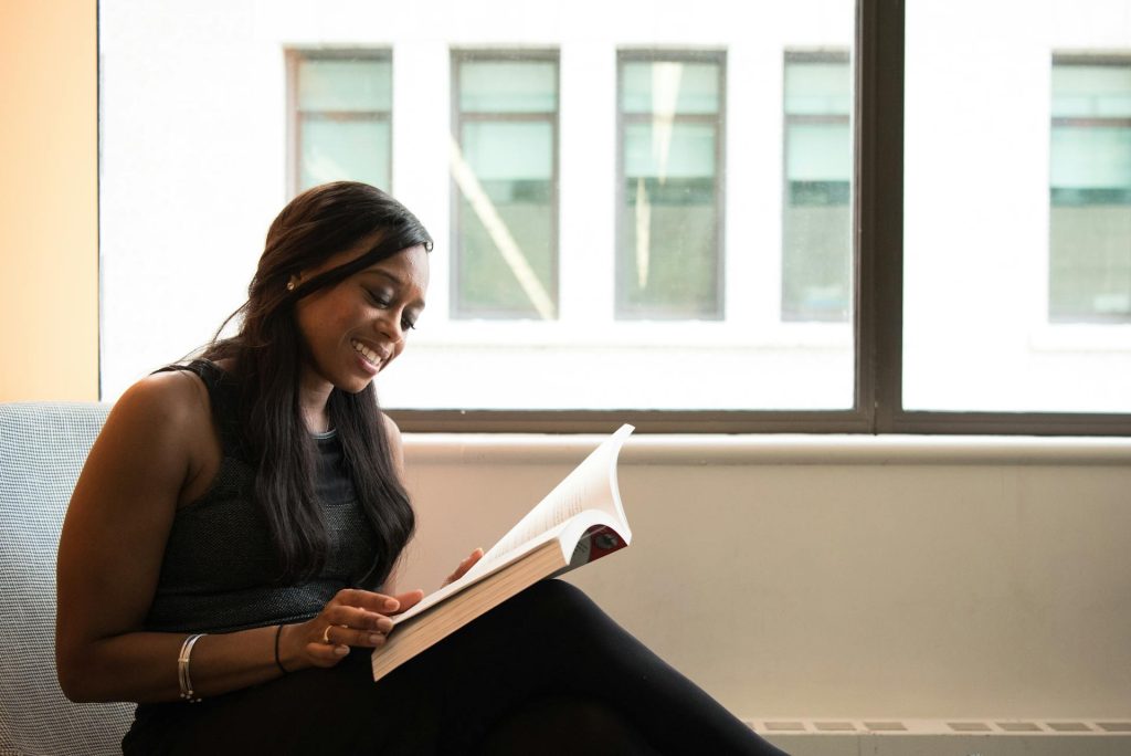 a woman sitting, reading and smiling